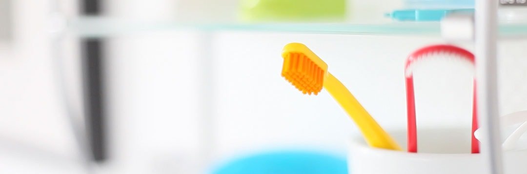 Utensilien wie, Zahnbürste im Glas und eine Zungenreiniger, die gut für die Zahnpflege sind