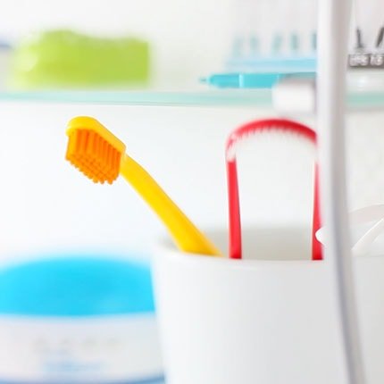Utensilien wie, Zahnbürste und Zungenschaber im Glas, die gut für die Zahnpflege sind