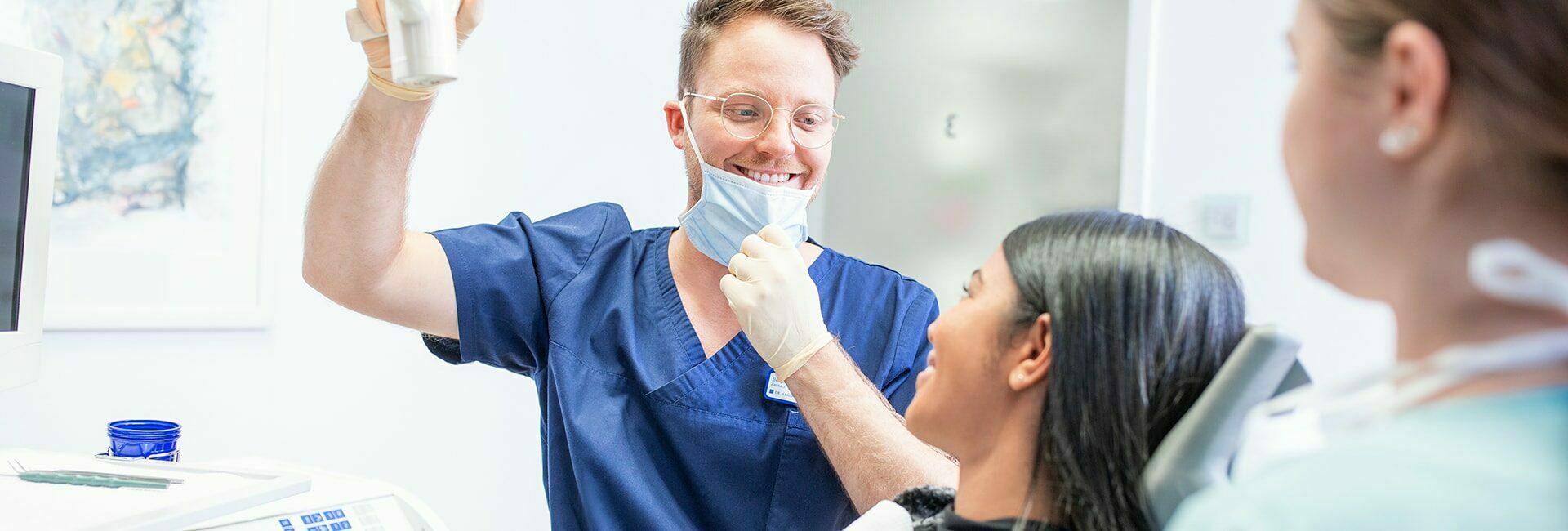 Zahnarzt lächelt Patientin an die auf dem Behandlungsstuhl sitzt